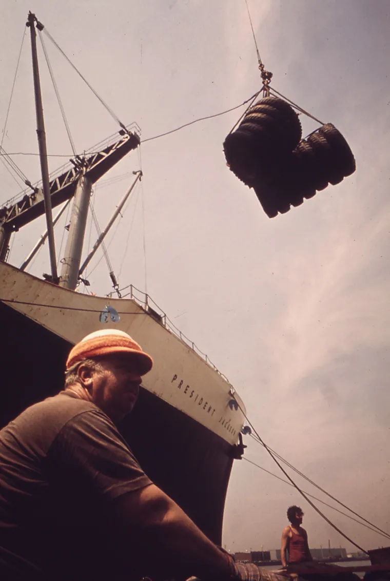 A longshoreman working cargo alongside a ship at a terminal