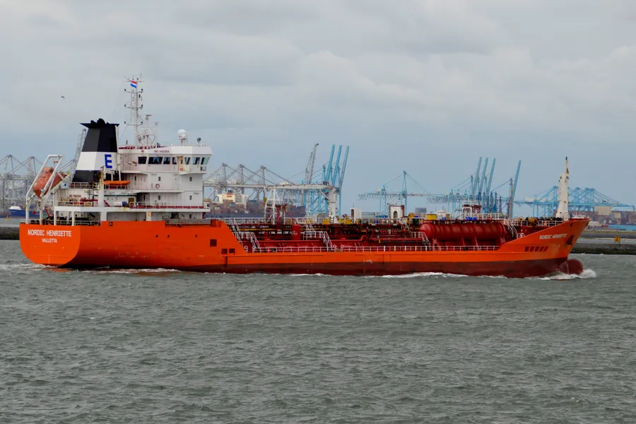 A chemical tanker under way in the Rotterdam approaches, container cranes behind